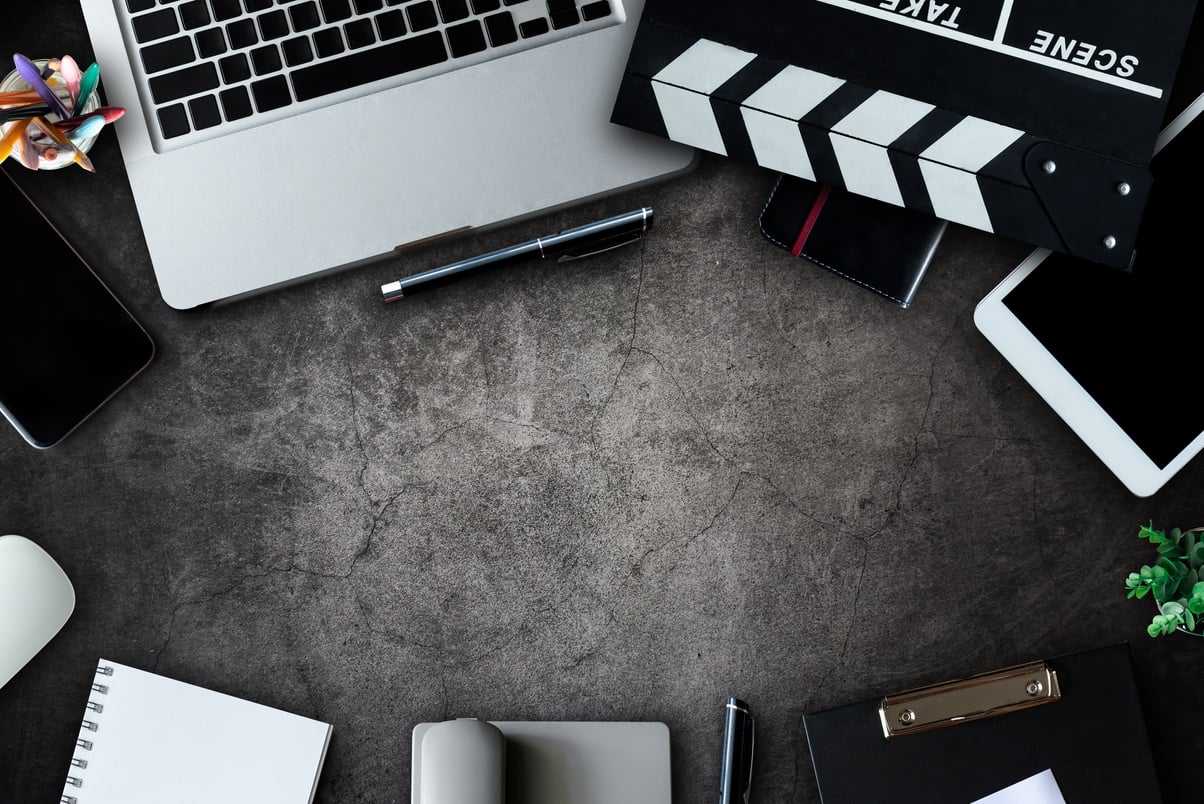 office stuff with Movie clapper, laptop, coffee cup, pen, notepad on the wood table top view shot.